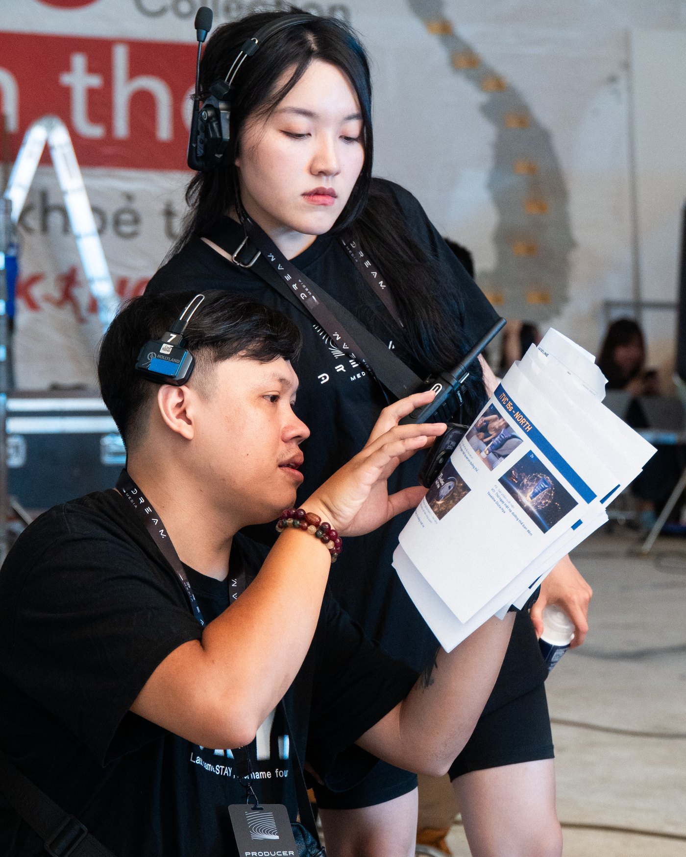 Producer in a headset checking the printed shot boards with a crew member on a Vaseline shoot