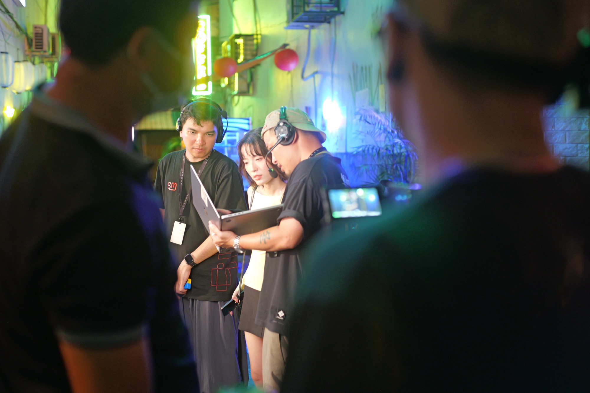 Director in a headset going through the plan on a laptop with the actress and a crew member during a Samsung Galaxy S24 night shoot
