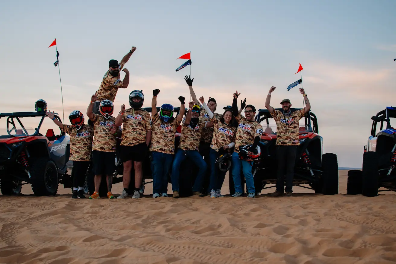 A large group of people standing with a fleet of Polaris RZR rentals at Little Sahara State Park for an all-inclusive adventure package.