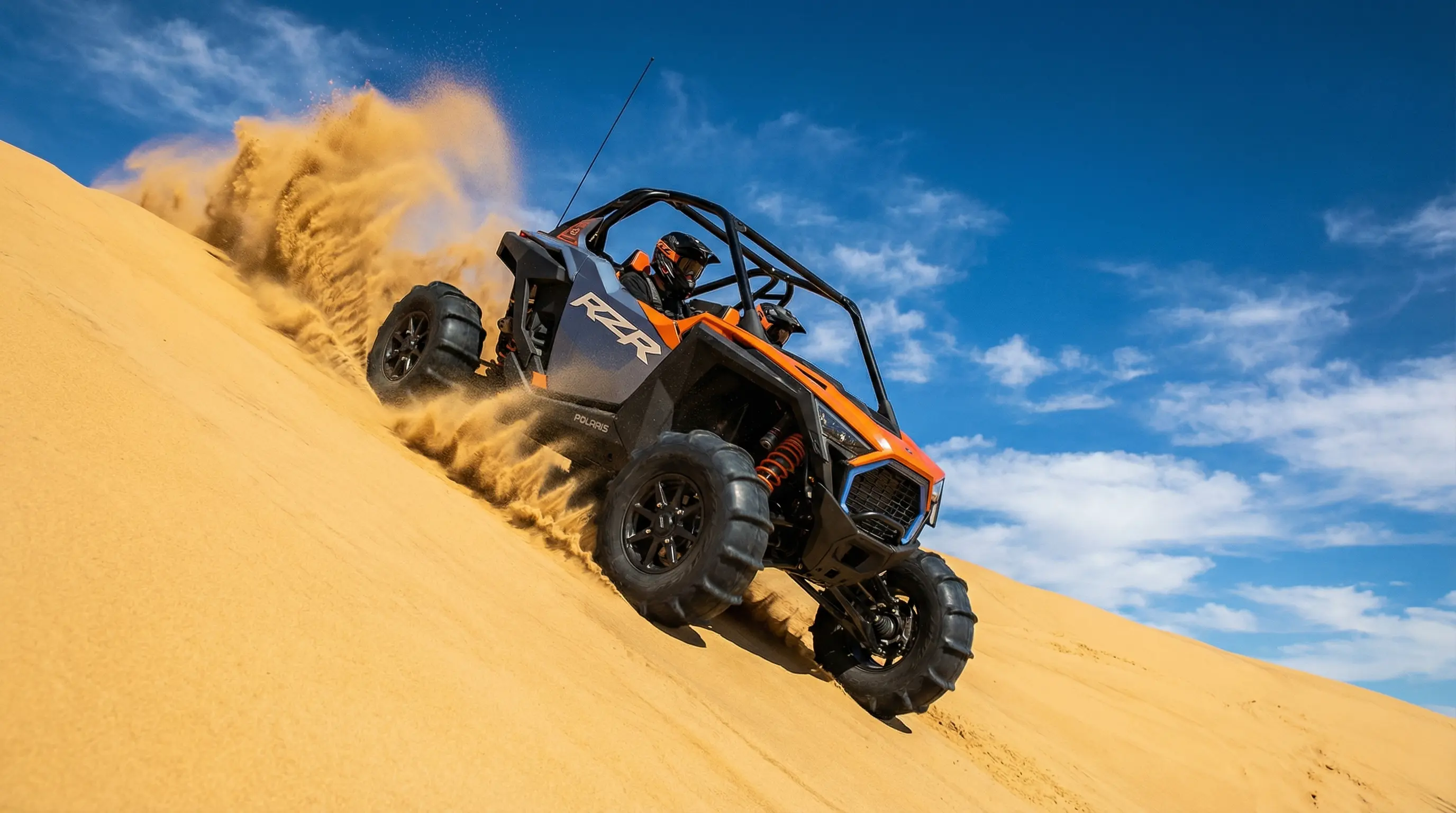 Low-angle action shot of a Polaris RZR Pro S climbing a massive sand dune wall.