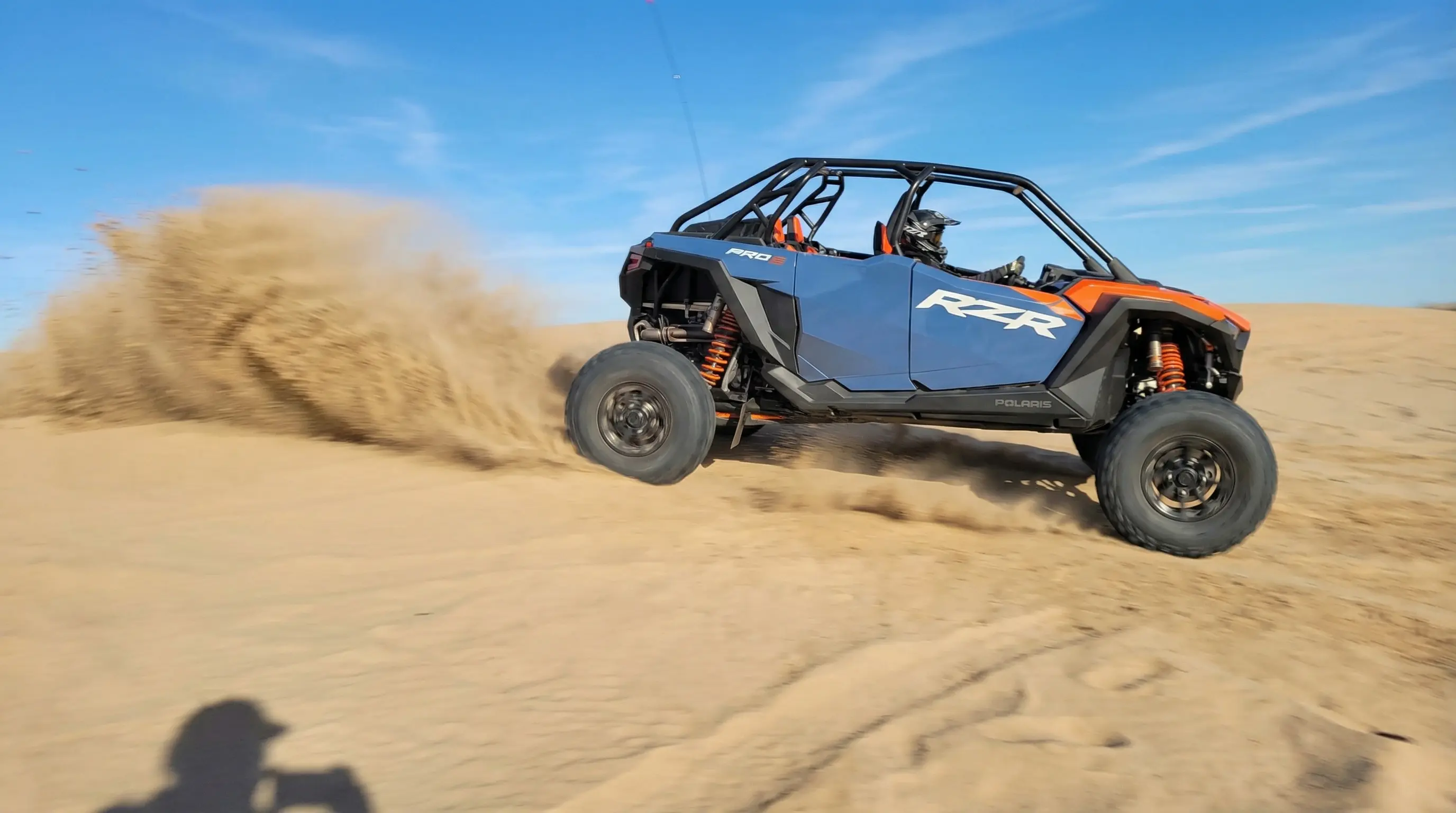 Candid action shot of a blue and orange Polaris RZR drifting on a sand dune, taken by a customer at Little Sahara State Park near Woodward, OK.