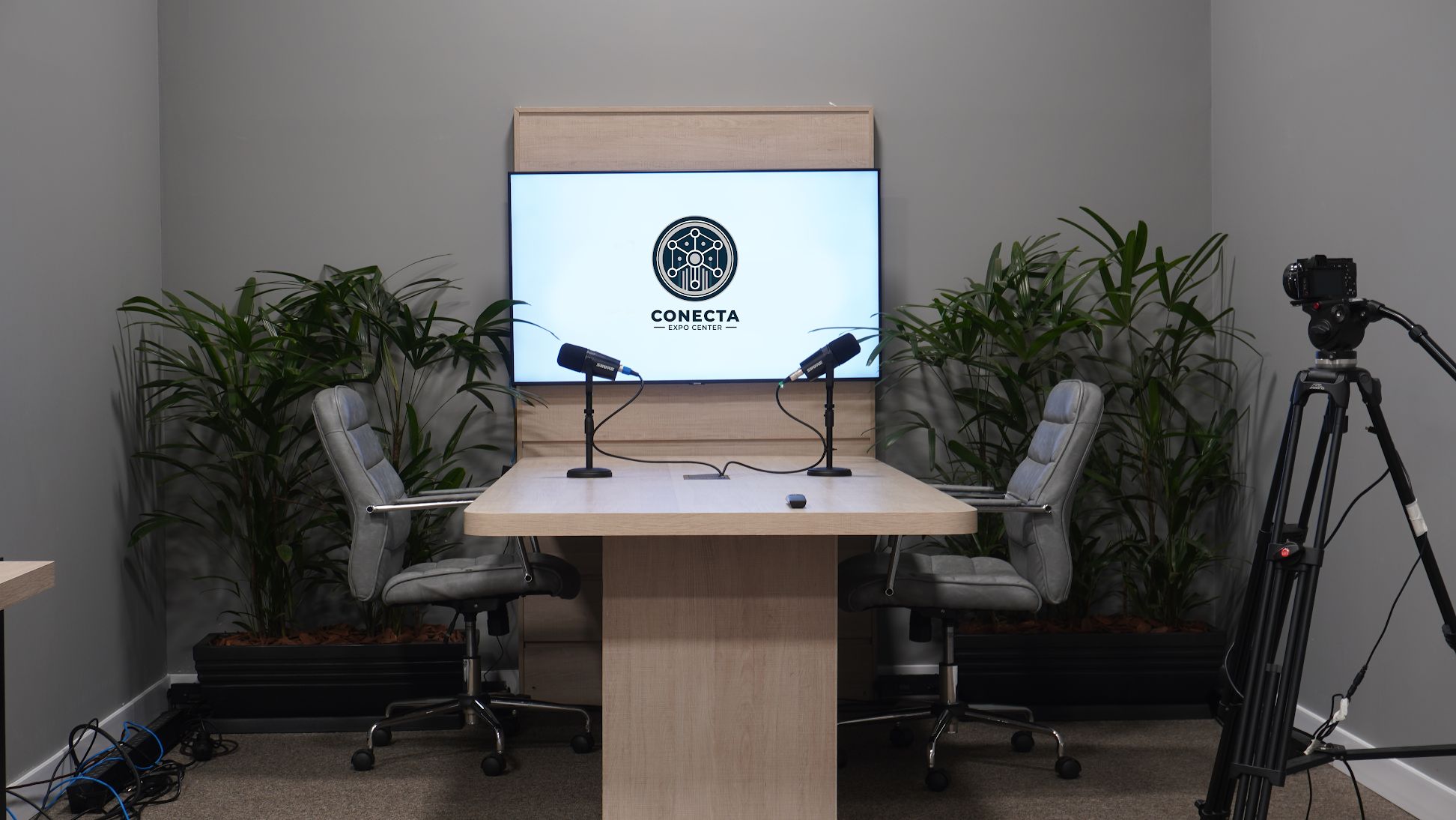 Estúdio da Conecta Arena com mesa, microfones, câmera e tela