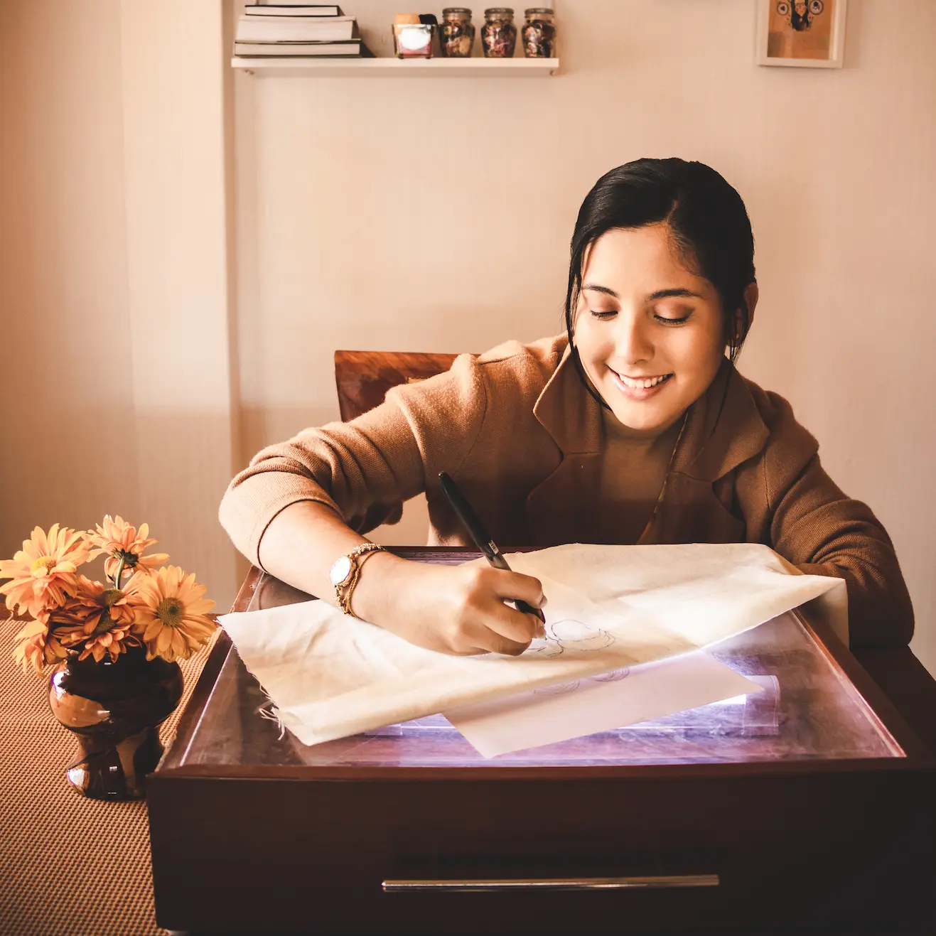 Person writing in an elegant leather-bound journal with handwritten notes and sketches, sitting at a rustic wooden desk with natural lighting, wearing a floral patterned shirt, top-down view showing the artistic process of journaling and creative writing