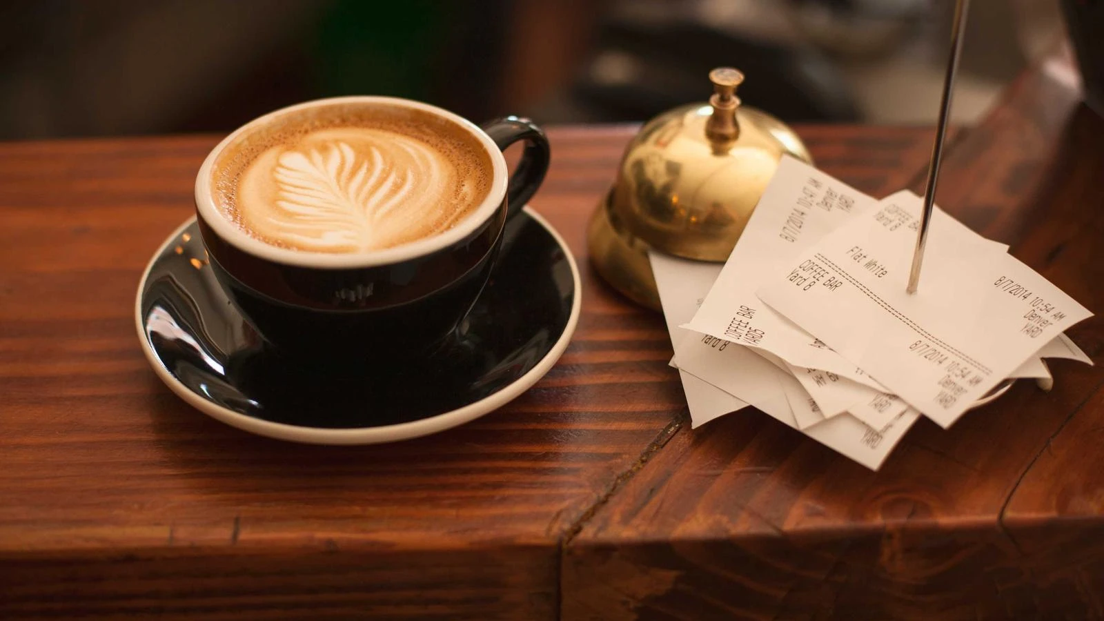 Latte art in a dark cup on a wooden café counter