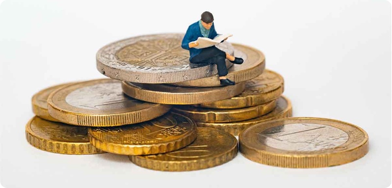 Man reading a book while sitting on a pile of coins 