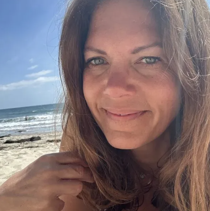 Danielle, a professional cuddler in Carlsbad, smiling on the beach
