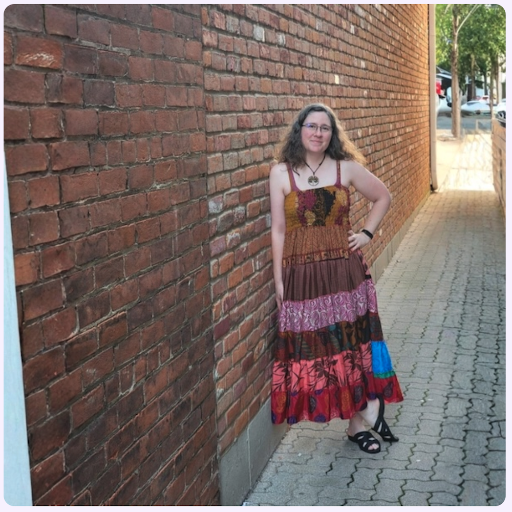 Emily Laura standing beside a brick wall on a Cincinnati sidewalk