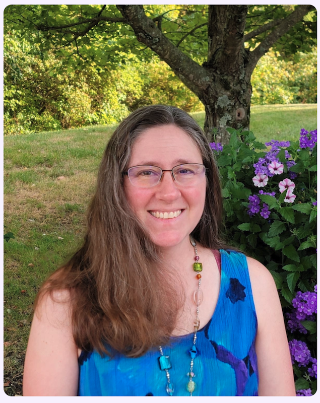 Emily Laura, a professional cuddler in Cincinnati, smiling outdoors beside a flowering garden