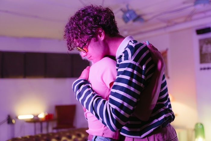 Two adults in a close, fully clothed embrace in a warmly lit room