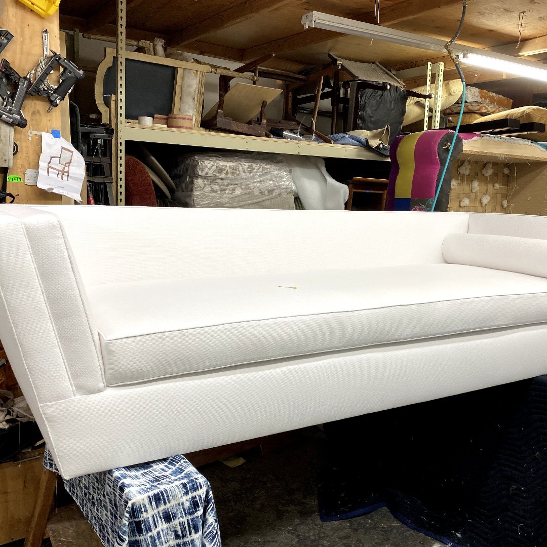 Custom white fabric sofa featuring a clean-lined modern silhouette and plush cushions.