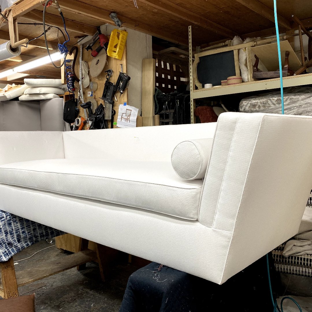 Detail shot of hand-finishing a white upholstered sofa in a professional workshop