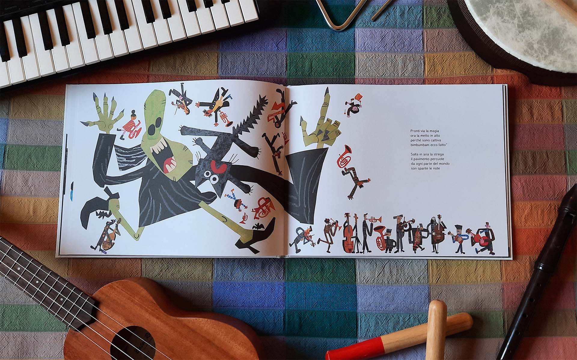 Doppia pagina con la strega verde che salta in aria insieme al gatto nero, mentre i musicisti e i loro strumenti volano via; il libro è aperto su una tovaglia a quadri, fra tastiera, ukulele, flauto dolce e tamburo