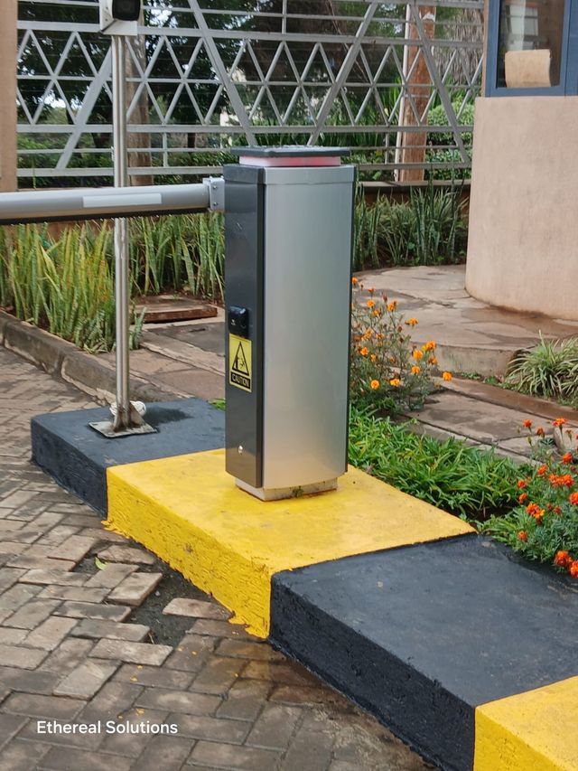 Stainless steel automatic boom barrier and CCTV pole at an office compound vehicle entrance in Nairobi