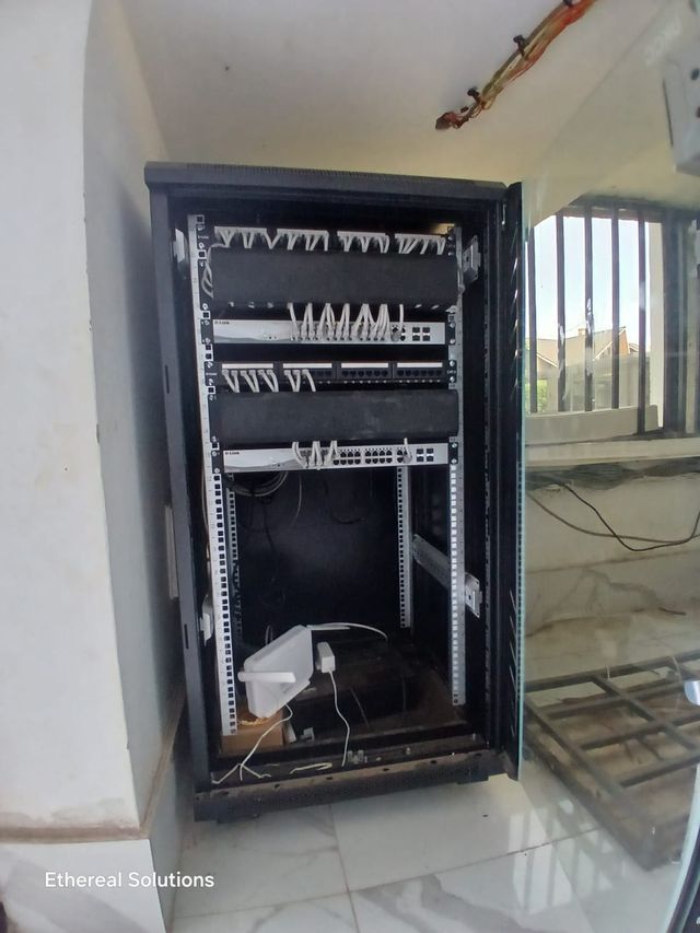 Floor-standing network cabinet with switches, UPS and router installed in a building corner