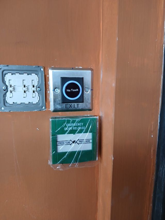 No-touch exit button and green break-glass emergency door release mounted beside a door