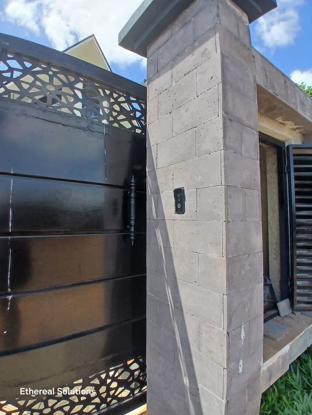Residential gate entrance with a video doorbell installed on the stone pillar