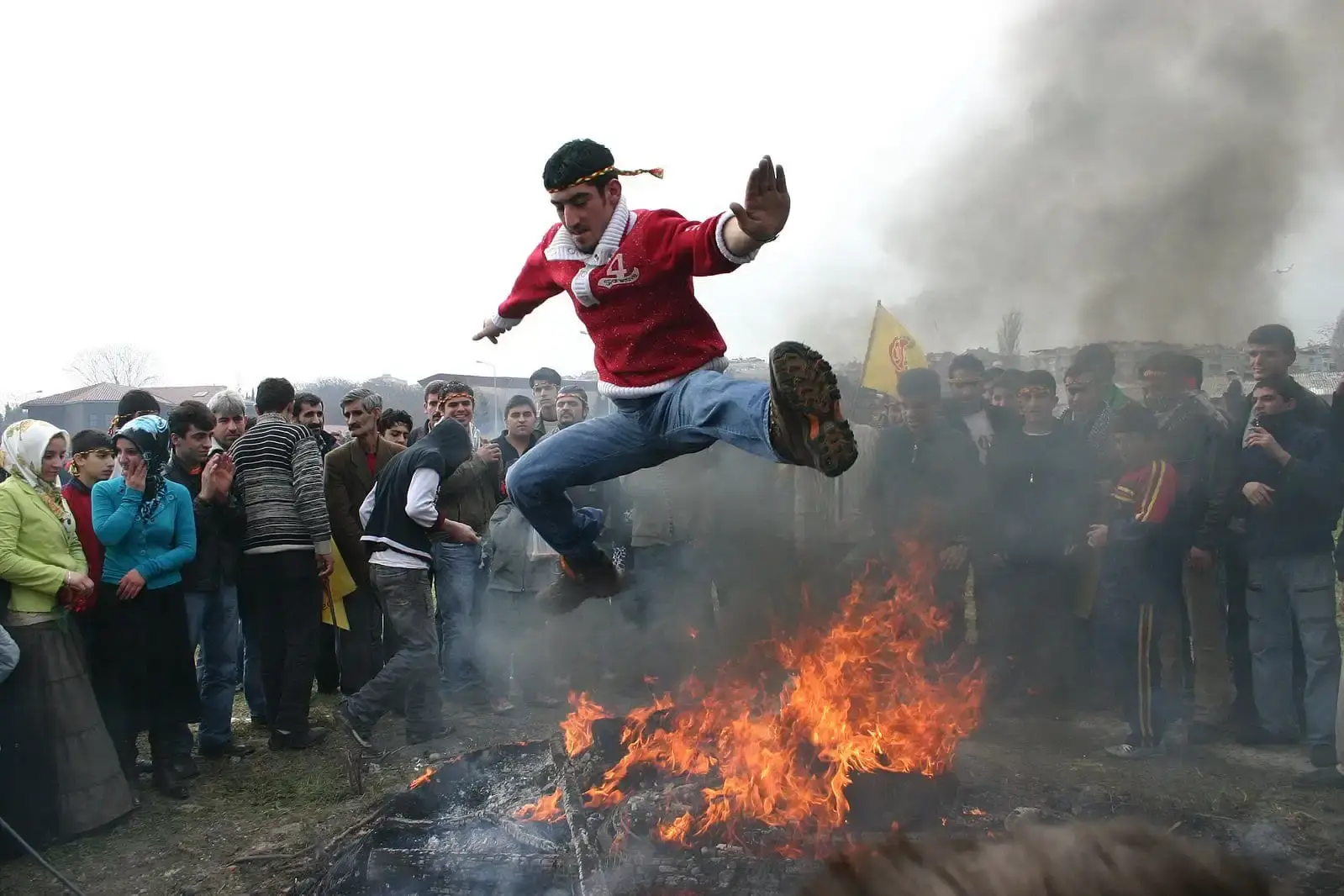 Man jumping across a small fire while crowd is watching