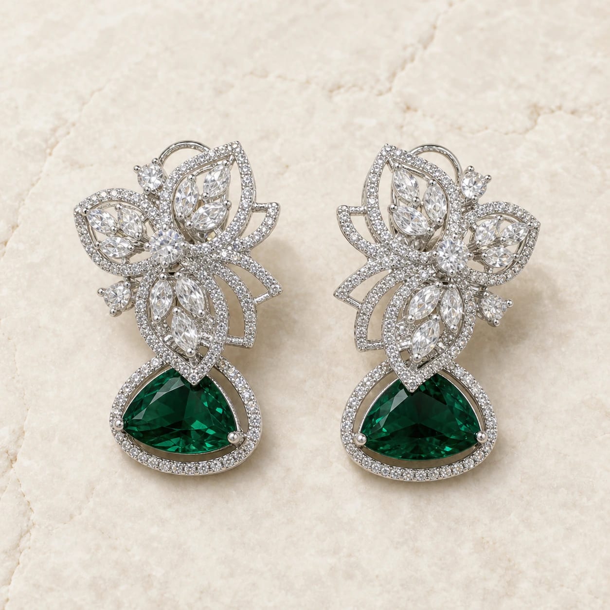 Emerald-green crystal statement earrings on warm ivory stone