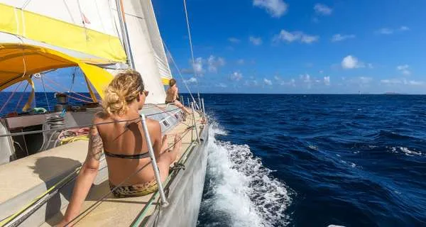 Female crew member sitting on the deck of a heeling sailboat on the open sea