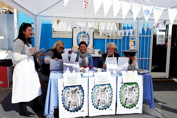 Volunteers selling Expressions Tea Towels at a fundraising stall for St Kilda Mums.