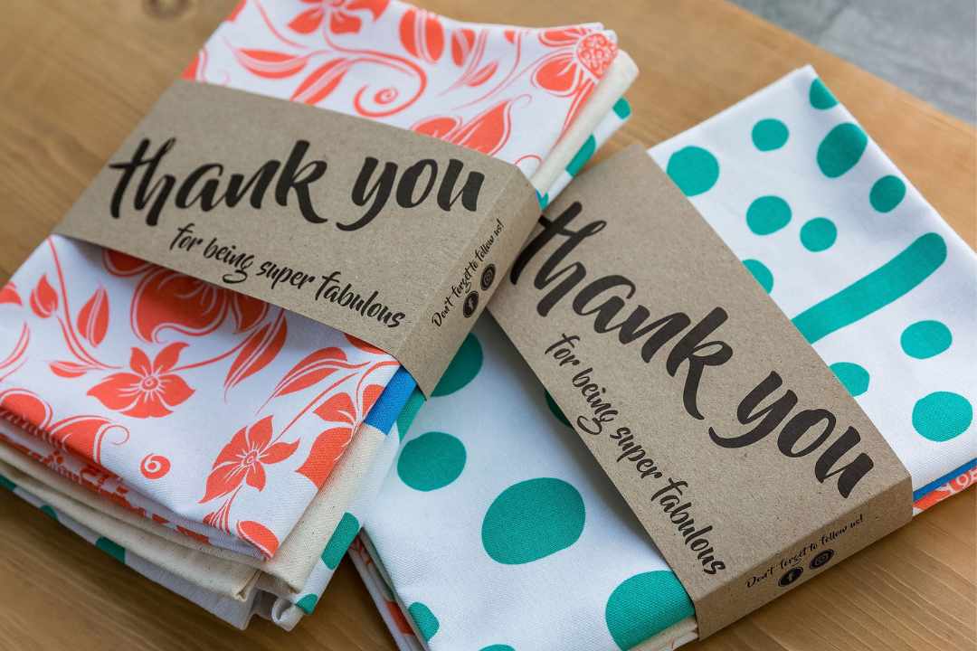 Thank you tea towels folded with kraft paper sleeves and "Thank you for being super fabulous" message