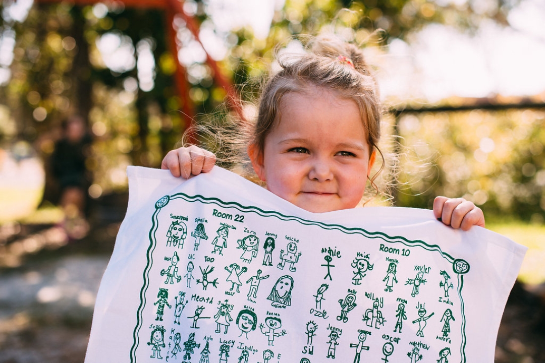 Child holding school fundraising screen printed tea towel