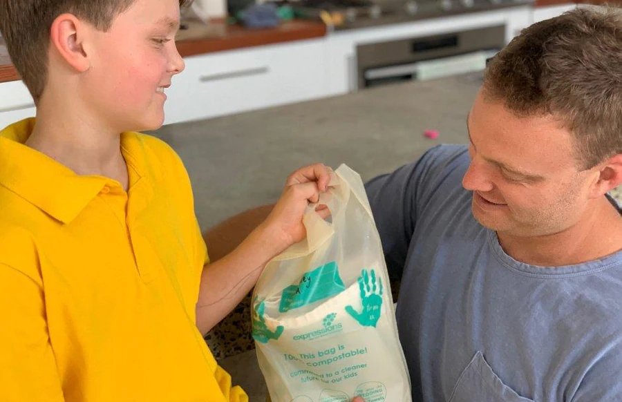 Father and child holding an Expressions compostable fundraising package.