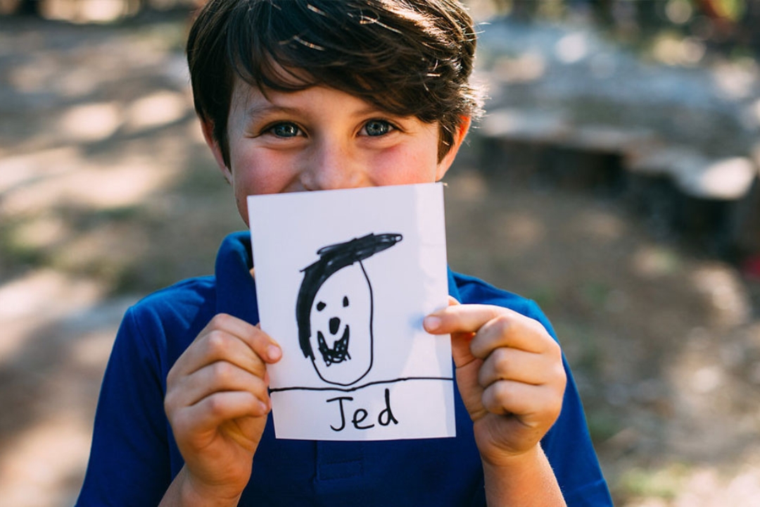Child holding drawing to be printed on school fundraising tea towel