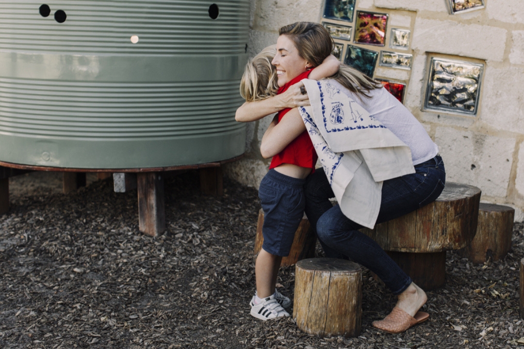 Mum and child hugging after being gifted a screen printed fundraising school tea towel