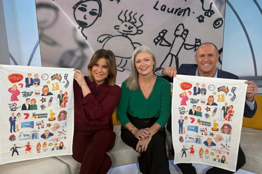 Expressions Fundraising's Emma with The Morning Show hosts Larry and Kylie, showcasing custom school tea towels created to celebrate 25 years of community fundraising.