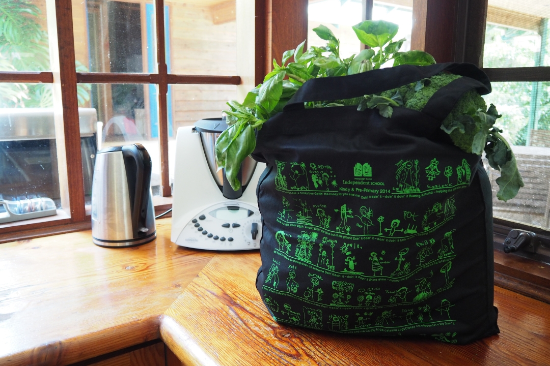 Black tote bag with green screen printed children's drawings for a childcare fundraiser