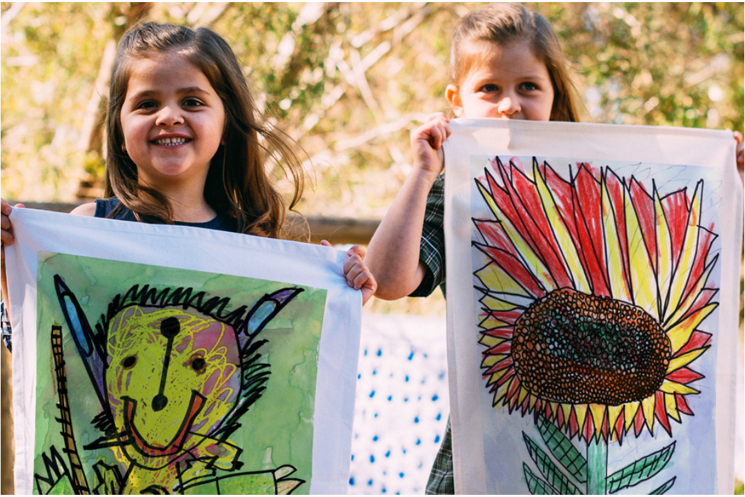 Expressions Fundraising team showcasing colourful school tea towel designs from across Australia.