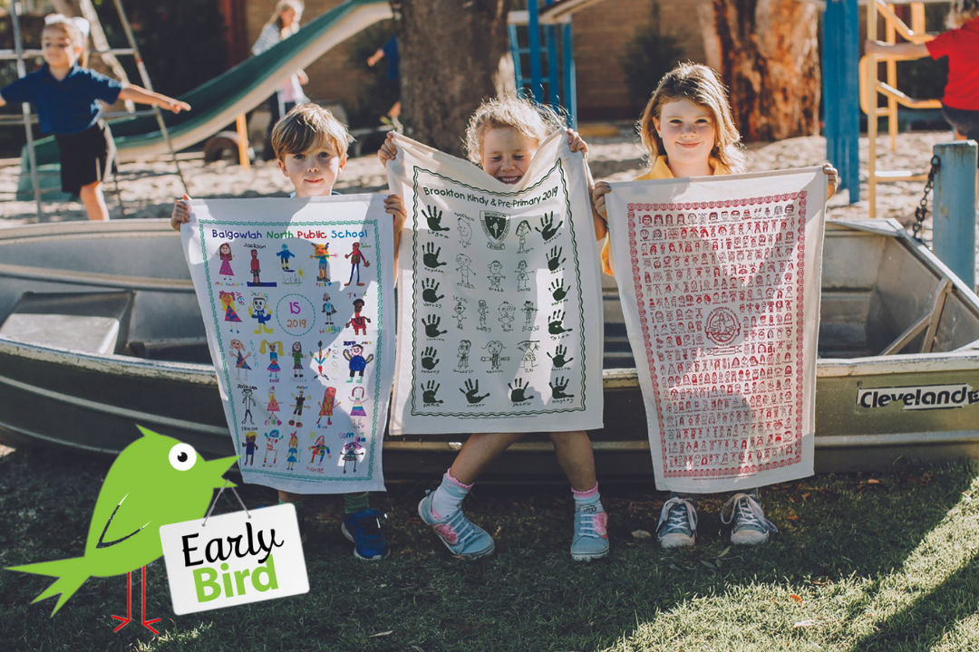 Three smiling children proudly holding colourful, student-designed tea towels in front of a playground. A green cartoon bird with a sign reading “Early Bird” highlights Expressions Fundraising’s 2025 promotion for bonus tea towels.