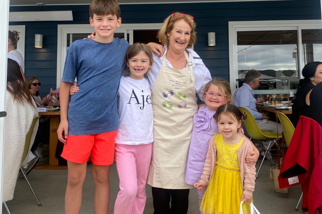 Smiling grandma with grandchildren wearing her personalised apron with children's artwork