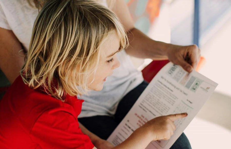 Child looking at an Expressions Tea Towel fundraiser order form with a parent, choosing fundraising options.