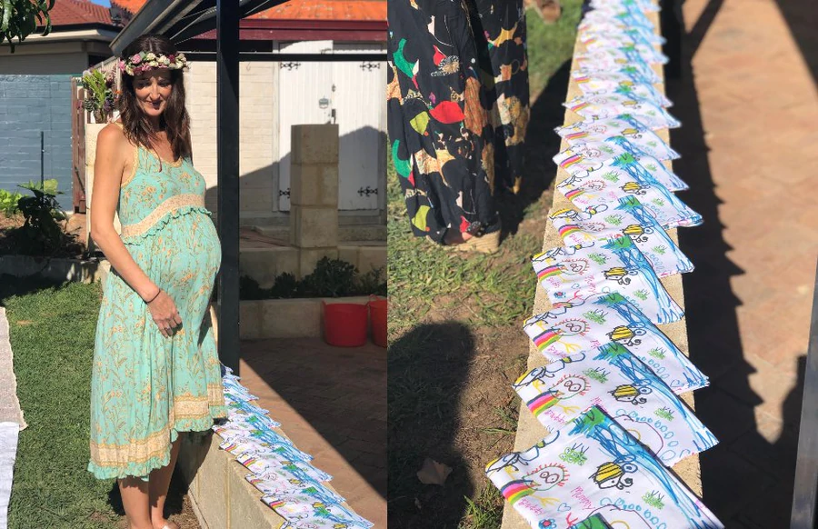 Pregnant woman at baby shower with personalised tea towels displayed featuring children’s artwork.