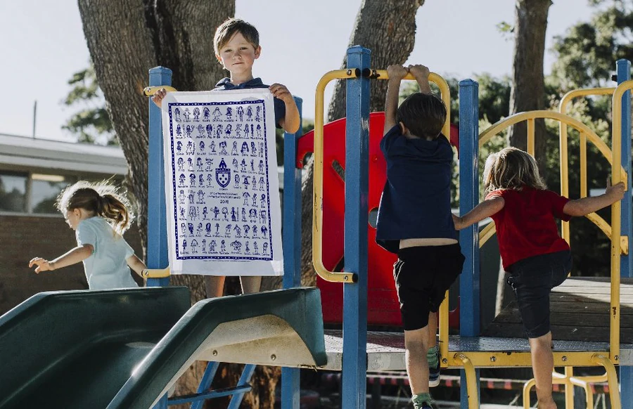 Child holding an Expressions Tea Towel fundraiser keepsake at Campbell Street Primary
