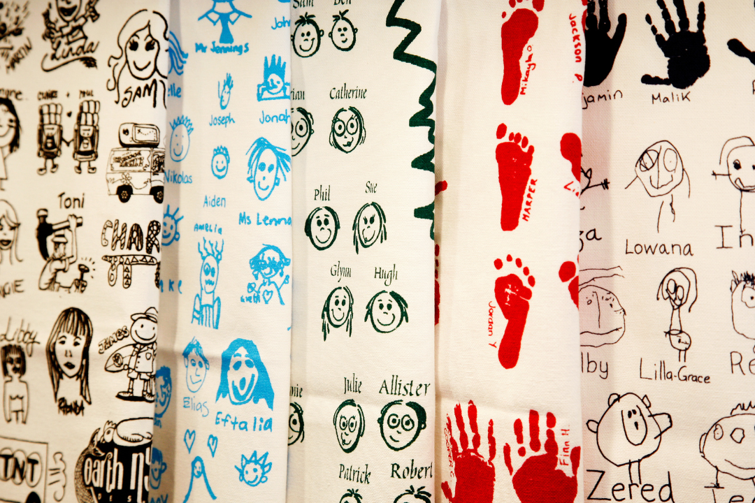 Collage of printed Expressions Tea Towels with children’s drawings, names and handprints