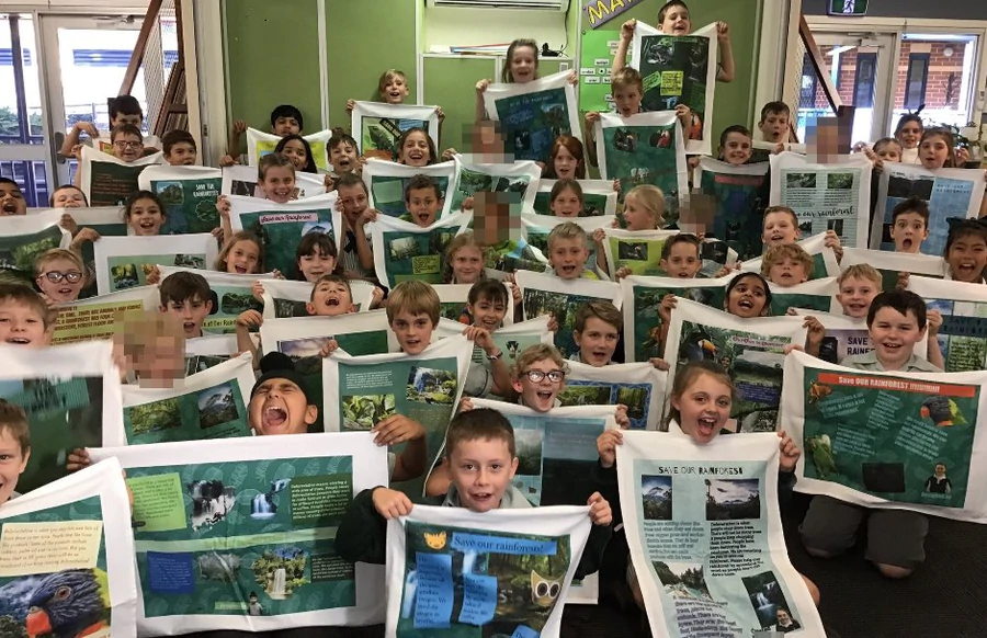 Group of Year 3 students holding rainforest-themed tea towel fundraisers created with Expressions Tea Towels in Australia.
