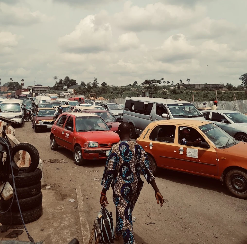 Image of a man ni the city of Ibadan, and some local taxis