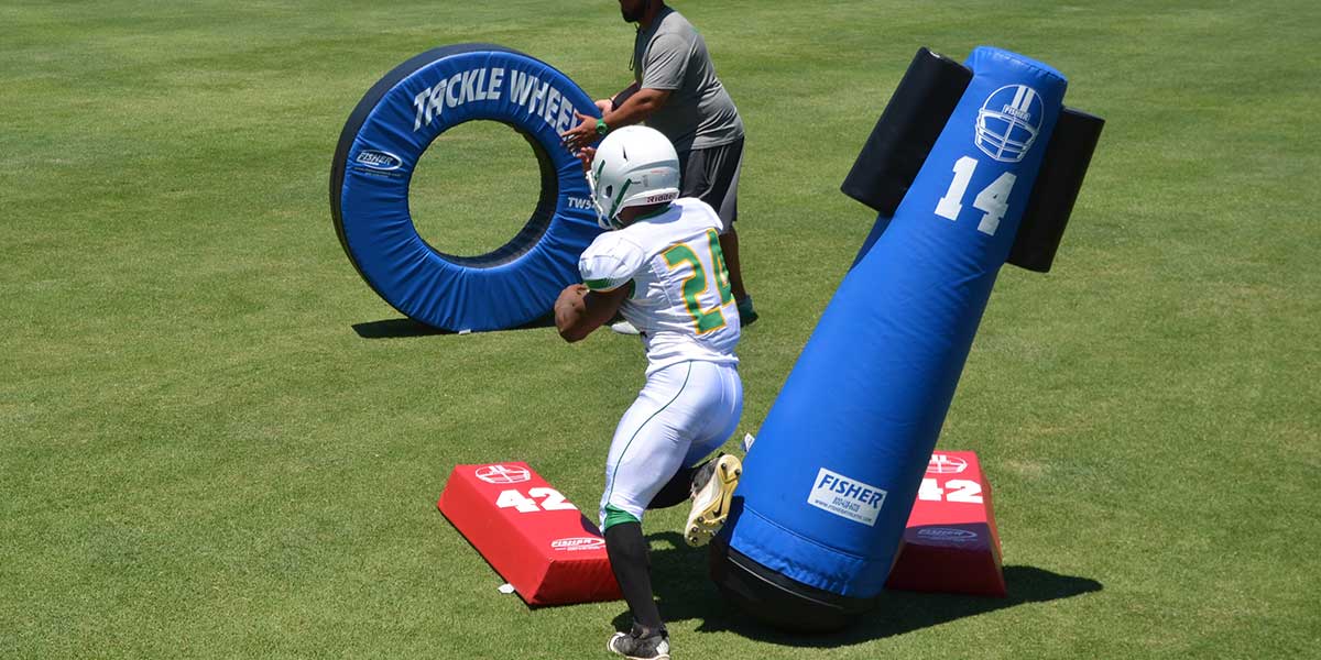 Varsity Pop Up Dummy 72'' Royal Blue with Wings on the field during daytime football training, with a player practicing tackling drills