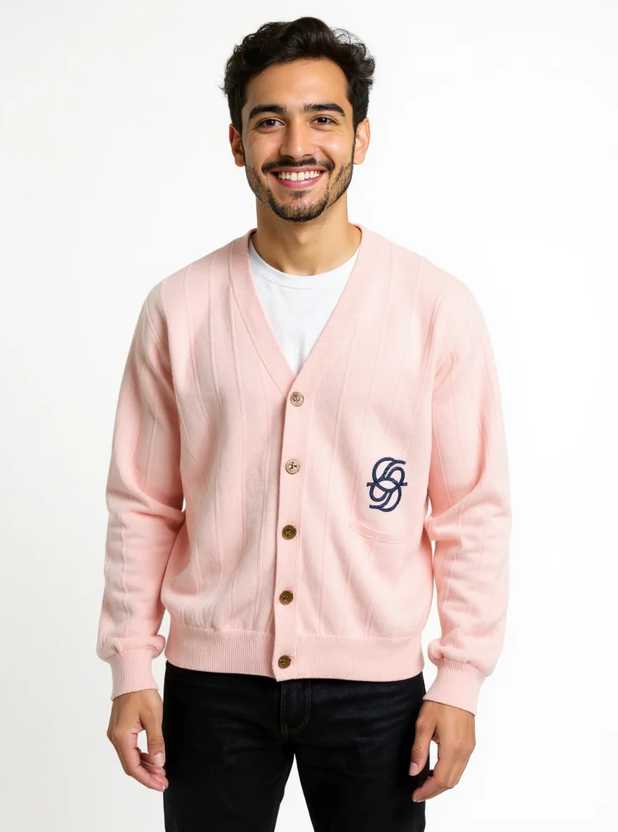 Male model wearing a light pink V-neck ribbed cardigan sweater with embroidered logo and brown buttons in a clean white studio.