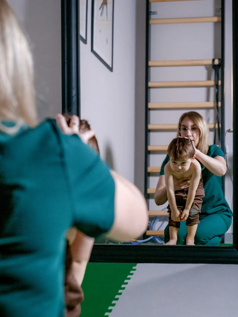 Fizjoterapeuta dziecięcy, który pracuje z dzieckiem ze skoliozą. 
