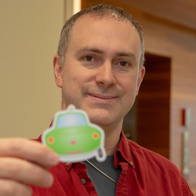 Portrait of Michael Dowden holding a Lexe sticker.