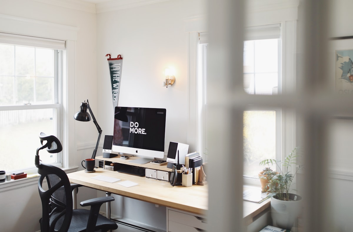 Home office with wooden desk, iMac, and black mesh chair