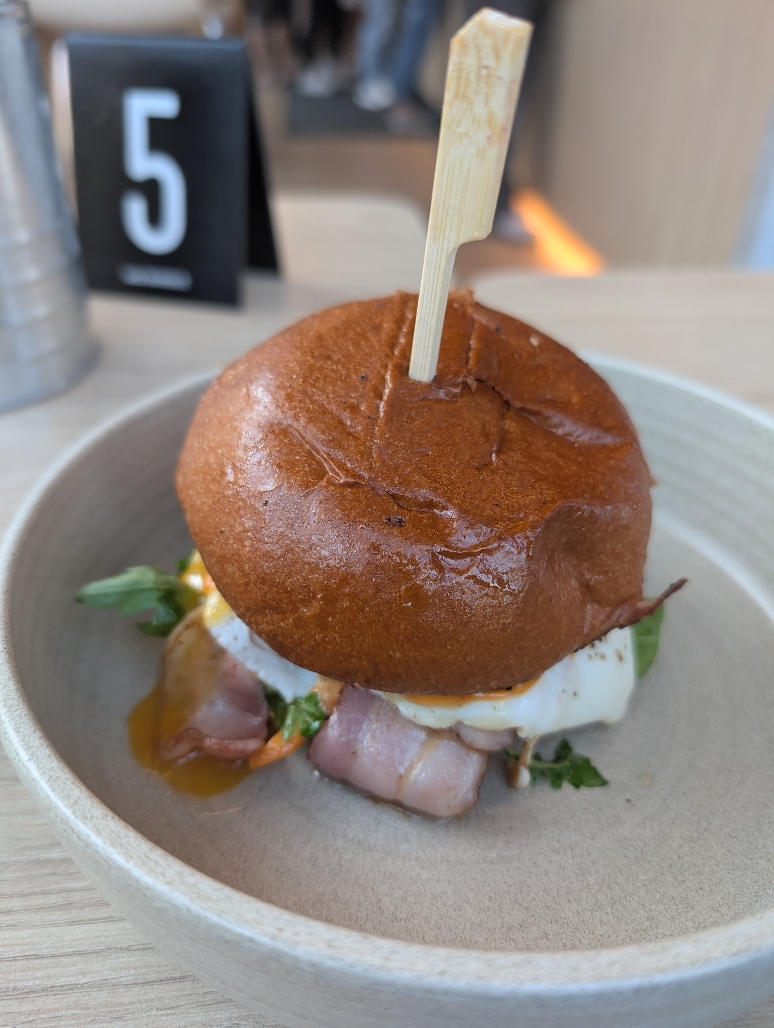 Brioš sumuštinis/burgeris su Šoninė, keptas kiaušinis, čederio sūris, karamelizu