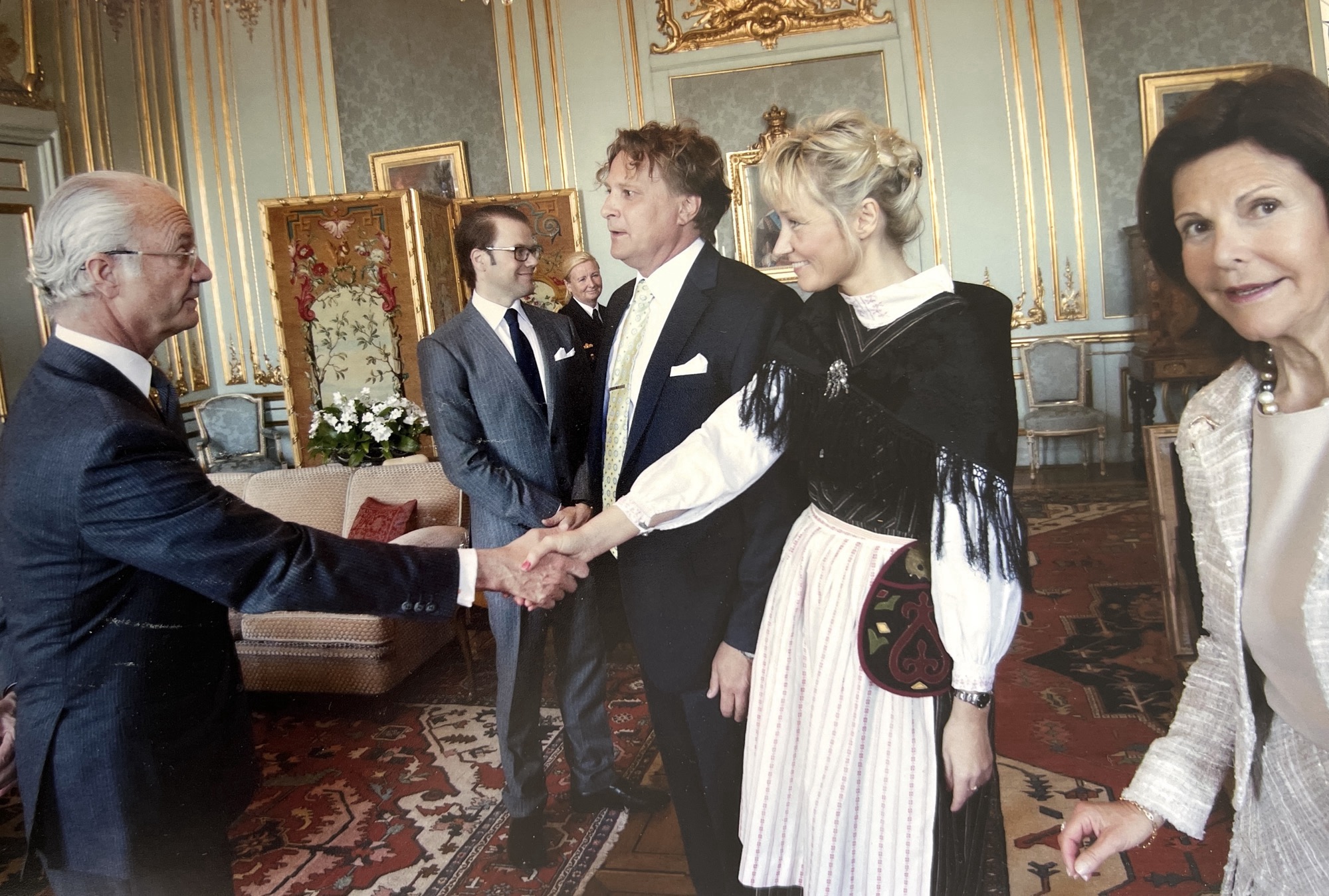 Tony Warren greeting King Carl XVI Gustaf at the Royal Palace in Stockholm, with Queen Silvia at right and Prince Daniel in the background