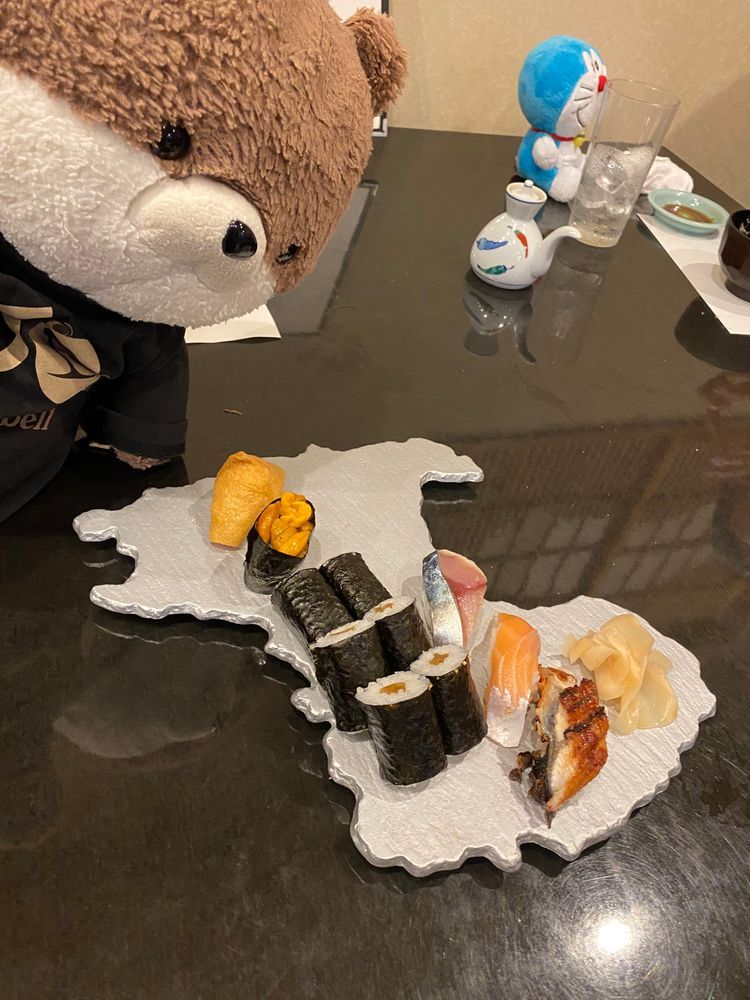 射水市内でお寿司を食べたよ。よく見たら、器が富山県の形になっているんだ！お刺身もお寿司も、何を食べてもとろけるようなおいしさだったよ🤤
お店の女将さんの接客が素晴らしくて、カワミちゃんを見るなり頭をなでなでして「いらっしゃい！よく来たね」って言ってくれたんだ。お孫さんもぬいぐるみ好きらしくて、しばらくぬいぐるみの話で盛り上がってしまったよ。旅先で、ぬいに優しいお店に会うと、楽しさも２倍になるよね。このお店、繁盛してほしいよ。
