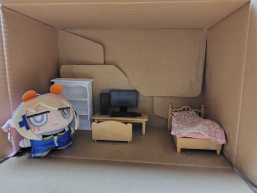 これがトイトイの家だ。
トイトイの宇宙船（輸送用段ボール）を再利用したものらしい。
とりあえずデスクトップPCがあるのはありがたい。しかし問題は布団だ。
枕が合わない・マットレスが薄い・掛け布団がペラペラ。
これは寝床とは呼べない。おいコチ、トイトイの為のオーダーメイドの物を出せ。