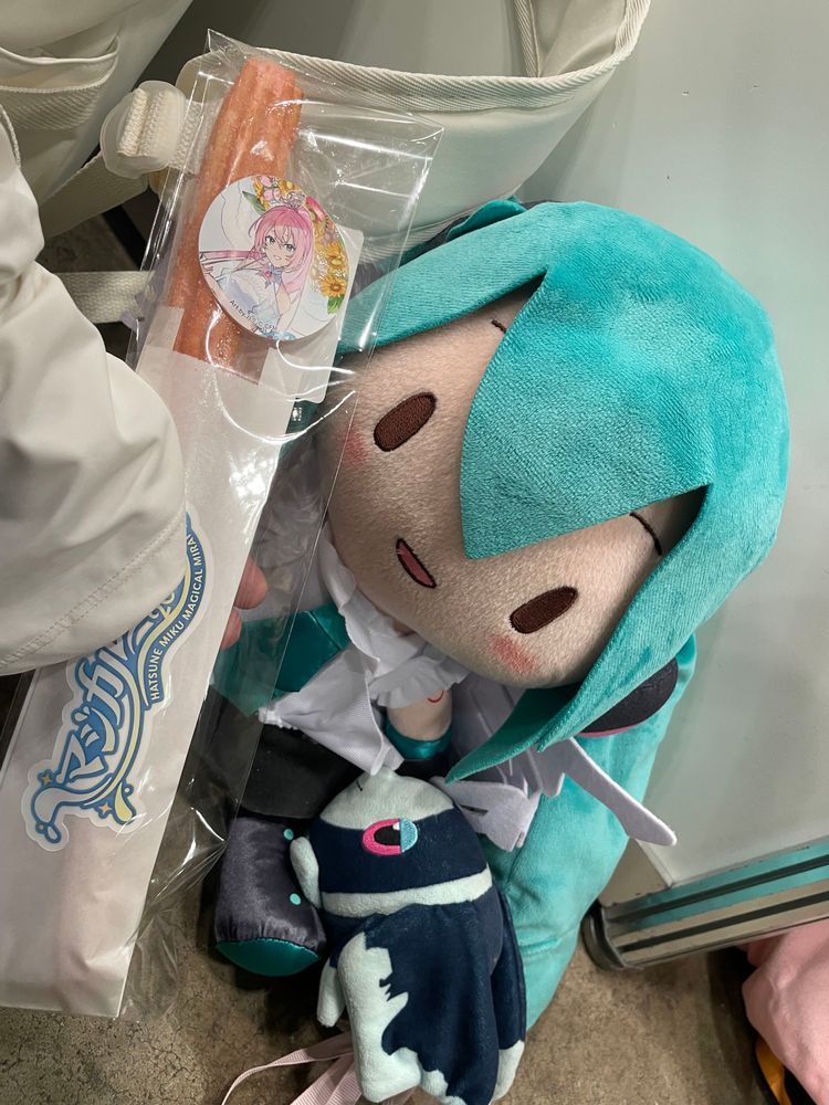 みずうみの そなーれ

みくちゃんたちから こんさーとの しょうたいじょうを うけとった ぼくらは、 ついに まじかるみらい2026の きかくてん かいじょうに やってきた！

みずうみの そなーれを いめーじした おようふくの みくちゃんが おでむかえ！🌻
ごしょうたい ありがとう！
また あえて うれしいな！

そして… ちゅろす！ どりんく！ あいす！ けーきの よよいの よい……😌

ちゅろすは、 るかさんを いめーじした ぴんくいろの ふらんぼわーずあじ！
さくさくで おいしい！
しかも なかの もちもちした ぶぶんが ちょっと ひんやりしてるんだ 
あげものを たべてるのに、 ひんやりしてて… 
すずしげな なつの こんさーとを ついきゅうした ことしの うんえいさんの こだわりを かんじたよ🤩

そして ぼくが いただいたのは、 ぴんくいろの どりんく！
これも るかさんを いめーじした ぴーちちょこぷりんどりんく…！
ぴーちちょこぷりんどりんく……？🤔
ふしぎだよね でも とっても おいしい！
ぴーちふうみの じゅーすに のって、 つめたい ちょこぷりんが つるつる のどを とおる… からだの なかから くーるだうん できちゃうよ🍫

さいごは、 ぴんくと しろの すてぃっくけーき… すいーとすとろべりーすてぃっく🍓 かわいい しーるつきだよ！
しっとり やわらかくて、あまい いちごと みるくの りっちな すてぃっくけーき！
コトコトスープさんと しぇあしながら いただいたんだけど、 ただでさえ おいしさ ばくれつ なのに、 そふとくりーむと あわせたら… おいしくないわけが ない！！

おいしい おかしに つられて ばつまるくんと なかよしの れんくんも あそびに やってきたよ🍌
みんなで おいしいじかん たのしかった〜！

